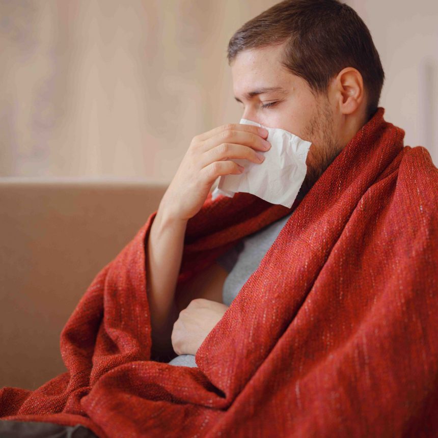Coronavirus. Sick man of corona virus lying down in sofa and recovery from illness in home. Blowing his nose. The concept of high temperatures. The person is seriously ill.